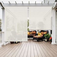 an outdoor living area with wooden flooring and white blinds on the side of the building