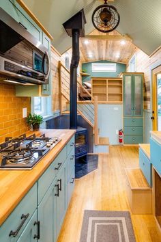 the interior of a tiny home with wood flooring and blue cabinets, including an oven