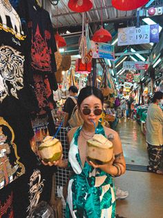 a woman holding a coconut drink in her hand while standing next to a store display