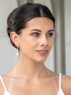 a woman in a white top is wearing earrings