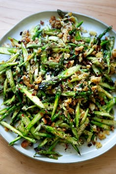 a white plate topped with asparagus covered in seasoning on top of a wooden table