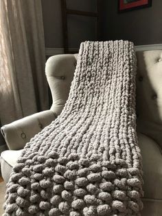 a gray blanket sitting on top of a couch next to a window