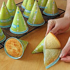 a person is holding a sandwich in front of some party hats on a table with other food items