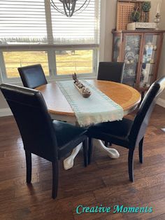 a dining room table with four chairs and a window