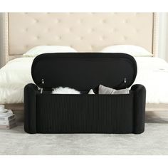 a bed with a white headboard and black storage bins on the bottom shelf