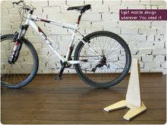 a white bicycle parked next to a wooden stand on top of a hard wood floor