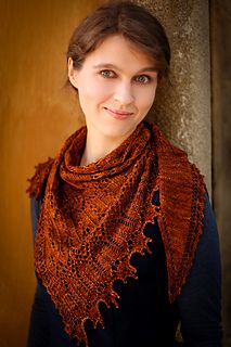 a woman wearing a brown shawl standing next to a wall