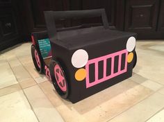 a cardboard box shaped like a train with wheels on the floor in front of a wooden cabinet