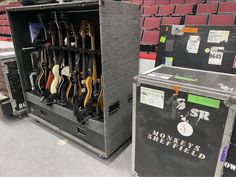 several guitars are stored in an old amp at a concert or showroom, with seats behind them