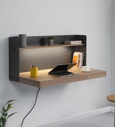 a laptop computer sitting on top of a wooden shelf next to a potted plant