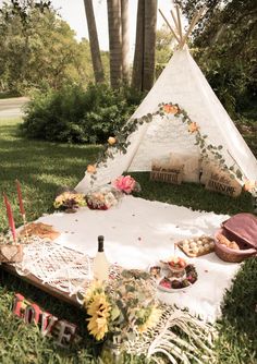 a teepee is set up in the grass with food and drinks on it for a picnic