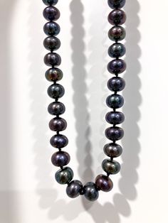 This beautiful necklace is a unique piece of jewelry that will make you feel elegant and sophisticated. It features natural freshwater black pearls, which are dyed with an organic dye to create a shiny surface and even colour. The pearls are in rondel shape, which means they are slightly flattened and have a diameter of 5 by 7 mm.  The necklace is 17 inches long and has a handmade knot between each pearl, which prevents them from rubbing against each other and ensures durability.  The necklace has a sterling silver clasp, which is easy to use and secure, and it adds a touch of elegance to the necklace. The necklace comes with a unique handmade packaging designed specially for this item. This necklace is perfect for anyone who loves pearl jewelry, black pearls, or silver jewelry. It would m Black Beaded Pearl Necklaces With Pearl Pendant, Black Pearl Pendant Beaded Necklace, Black Beaded Pearl Necklaces With Pearl Charm, Black Beaded Necklace With Pearl Pendant, Black Beaded Necklaces With Pearl Pendant, Black Pearl Necklace With High Luster For Gift, Black Pearl Necklace With Round Bead Pendant, Black Pearl Necklaces With Pearl Charm, Black Pearl Necklace With Pearl Charm