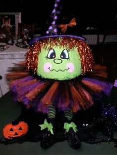 a green and purple halloween costume sitting on top of a table next to pumpkins