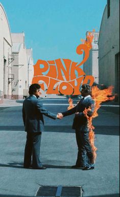 two men shaking hands in front of an orange and black sign that says pink floyd