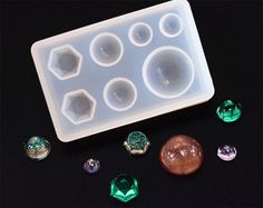 an ice tray filled with lots of different kinds of jewel stones on top of a black surface