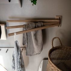 two wooden clothes racks are hanging on the wall next to a laundry basket and towel rack