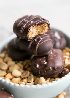 chocolate covered peanut butter balls stacked on top of each other in a bowl with peanuts