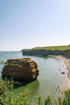 people are swimming in the water near some cliffs