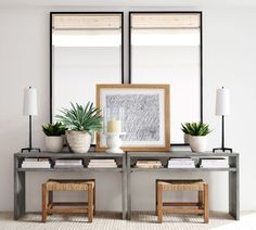 a table with some plants on top of it and two mirrors in front of it