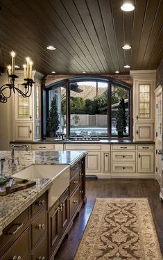 a large kitchen with white cabinets and marble counter tops, along with an area rug on the floor