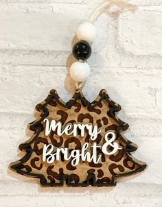 a wooden christmas tree ornament hanging on a white brick wall with black and white bauble