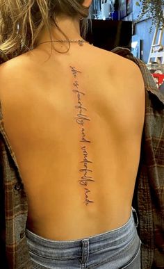 the back of a woman's upper body with writing on her left arm and chest