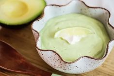 an avocado dip in a white bowl with a wooden spoon next to it