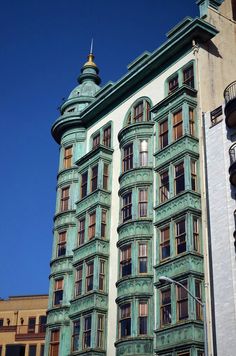 an old building with many windows and balconies on the top floor, against a blue sky