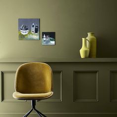 a brown chair sitting in front of a wall with two vases on top of it