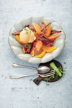 a white bowl filled with assorted fruit and ice cream on top of a table