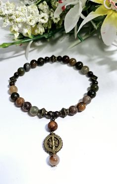 This is a beautiful brown gemstone and Bronze bracelet. It is lovingly handmade to a high standard using 6mm genuine A grade Picasso Jasper and Indian Agate gemstones,  alongside 4mm Snowflake Obsidan beads that are highlighted with antique bronze tibetan style beads and finished off with a beautiful dangling charm which dangles from the bracelet beautifully with an antique bronze bead. Agate cleanses and stabilises the aura, eliminating and transforming negativity. Agate enhances mental functio Spiritual Brown Beaded Bracelets With Gemstone Beads, Handmade Spiritual Bronze Beaded Bracelets, Brown Gemstone Beads Bracelets For Jewelry Making, Spiritual Brown Gemstone Beaded Bracelets, Spiritual Handmade Bronze Beaded Bracelets, Brown Gemstone Beads For Jewelry Making, Spiritual Brown Rosary Bracelet With Beads, Brown Rosary Bracelet For Meditation, Brown Beaded Bracelets For Jewelry Making