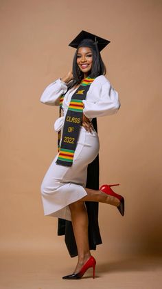 a woman in a graduation gown posing for the camera with her legs spread out, wearing high heels and a colorful sash