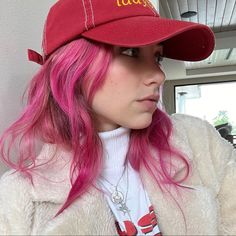 a woman with pink hair wearing a red hat that says lady on the front and side