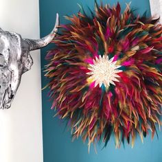 an animal's head is next to a colorful wall decoration with feathers on it