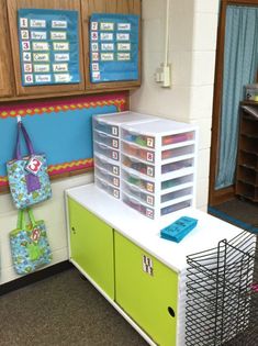 a classroom with lots of bins and baskets on the desk, next to a bulletin board