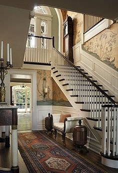 a staircase leading up to a living room and dining room area with chandelier