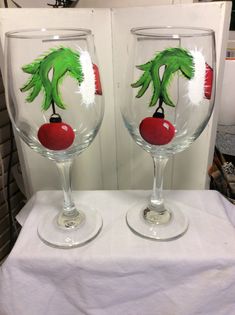 two wine glasses with painted designs on them are sitting on a white tablecloth covered surface