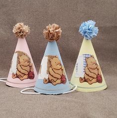 three party hats with winnie the pooh on them, one has a blue bow