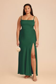 a woman in a green dress with her legs slited up and holding a bouquet