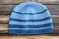 a knitted blue and gray hat sitting on top of a wooden table