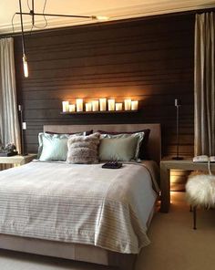 a large bed sitting next to a window with candles on the headboard and night stands