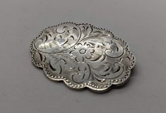 Superb vintage Burkhardt sterling silver floral engraved brooch measuring 1.5 inches long. Oval floral engraved medallion brooch with scalloped edges. There is a slight amount of tarnish on the back, the buyer can easily polish this off. It is otherwise, in great vintage condition. The back may look like it is dented, but it is not, it's most likely a reflection. I'll ensure your order is fulfilled as requested. Visit my shop at: newagainclassics.ca Silver Hallmarked Oval Brooch, Silver Hallmarked Oval Brooches, Silver Oval Hallmarked Brooch, Silver Oval Brooches Hallmarked, Classic Oval Silver Brooches, Oval Sterling Silver Brooch In Silver, Silver Filigree Oval Brooches, Silver Oval Filigree Brooches, Oval Silver Sterling Silver Brooches