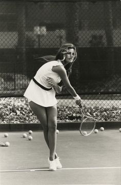 a woman holding a tennis racquet on top of a tennis court with balls in the background