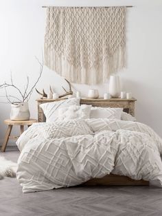 a bed with white comforter and pillows in a room next to a wooden table