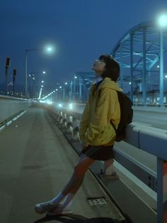 a man standing on the side of a bridge at night with his back to the camera