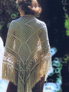 a woman wearing a crocheted shawl with fringes on her shoulders and back