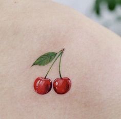 two cherries on the back of a woman's shoulder