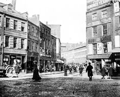 an old black and white photo of people walking on the street in front of buildings