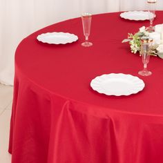 a red table topped with white plates and flowers