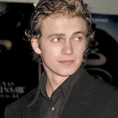 a man with curly hair wearing a black suit